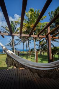 a hammock on a deck with palm trees at Pousada Santu Noronha in Fernando de Noronha