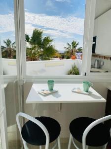 een witte tafel met twee stoelen en een raam bij Costa Adeje-Sunny!Modern!Sunset!Ocean View! in Adeje