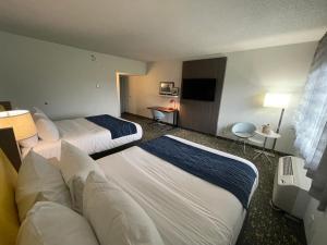 Habitación de hotel con 2 camas y TV de pantalla plana. en Saint Louis Airport Hotel en St. Louis