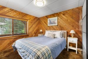 a bedroom with wooden walls and a bed and a window at Seabeck House & Cottage on Hood Canal in Seabeck
