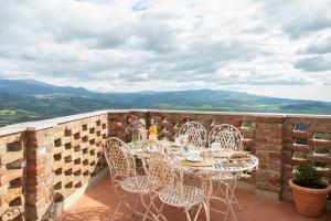 eine Terrasse mit einem Tisch und Stühlen an einer Ziegelwand in der Unterkunft Il Borghetto - La Casa di Elba, Terrazzo panoramico in Val d'Orcia in Castelnuovo dellʼAbate