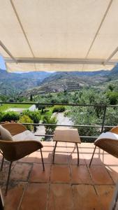 a balcony with chairs and a view of the mountains at La Almunia del Valle in Monachil