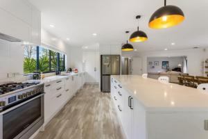 une grande cuisine blanche avec des placards blancs et une grande fenêtre dans l'établissement Ultimate 5-Bedroom Rural Poolside Oasis - Auckland, à Albany