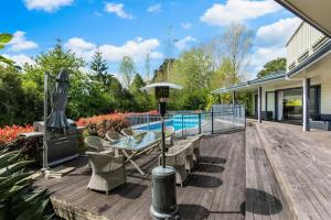 une terrasse avec une table, des chaises et une piscine dans l'établissement Ultimate 5-Bedroom Rural Poolside Oasis - Auckland, à Albany