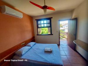 1 dormitorio con 1 cama, ventilador de techo y ventana en Branca Tropical Brasil Residencial- Taperapuan, en Porto Seguro