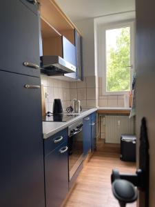 a small kitchen with blue cabinets and a window at Wohnen am Wanderbahnhof Iserlohn in Iserlohn