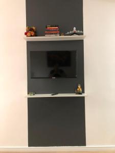 a black and white shelf with a tv on a wall at Studio Próx 25 de Março, República , José Paulino. in Sao Paulo
