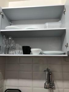 a kitchen shelf with plates and glasses on it at Studio Próx 25 de Março, República , José Paulino. in Sao Paulo