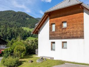 a white building with a wooden roof with a mountain at Alpen family apartment Bergfreunde near skilift and golf course in Bad Kleinkirchheim