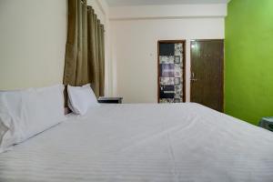 Super OYO Hotel Elite Inn في Korādih: سرير أبيض كبير في غرفة ذات جدار أخضر