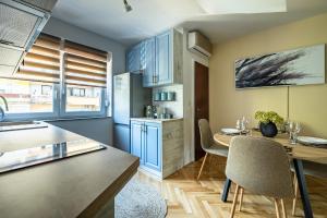 cocina con armarios azules, mesa y sillas en Apartman Sara, en Ðakovo