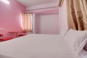 KorādihにあるSuper OYO Hotel Elite Innのベッドルーム(白いベッド1台、赤いテーブル付)