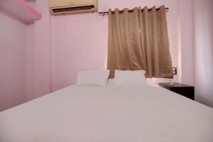 a white bed in a room with a window at Super OYO Hotel Elite Inn in Korādih