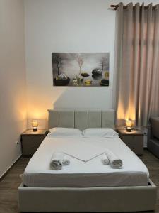 een slaapkamer met een wit bed met 2 lampen en een schilderij bij Gex apartments in Tirana