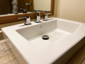 a white sink with two faucets in a bathroom at Hotel Carmacks in Carmacks