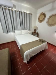 1 dormitorio con cama blanca y suelo de baldosa roja en Creta Hotel & Suites, en Mazatlán