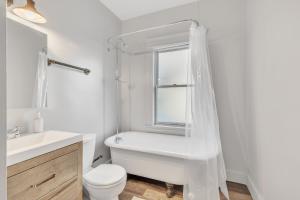 a white bathroom with a tub and a toilet and a window at Charming Cleveland Haven Duplex in Cleveland