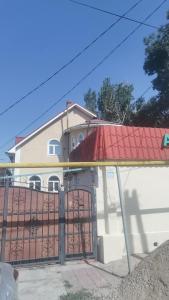 ein Haus mit einem Tor und einem roten Dach in der Unterkunft Laola民宿 in Almaty