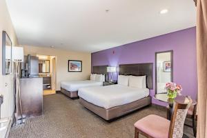 two beds in a hotel room with purple walls at Grand Legacy At The Park in Anaheim
