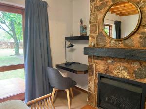 a living room with a stone fireplace and a mirror at Critchely Stone Villa, Dullstroom in Dullstroom