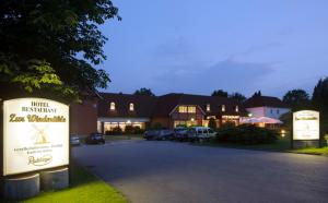 a building with a sign in front of a parking lot at Hotel Zur Windmühle in Stapelfeld