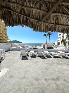 a beach with chairs and a straw umbrella and the ocean at Creta Hotel & Suites in Mazatlán