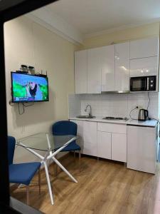 eine Küche mit einem Tisch und Stühlen sowie einen TV an der Wand in der Unterkunft Apartment. of the city. in Kutaissi