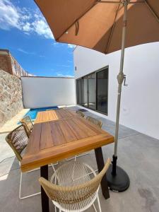 a wooden table with chairs and an umbrella at CASA PITAHAYA con alberca privada Col El Mirador in San Carlos