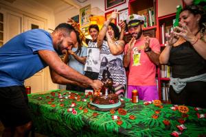 Un homme qui coupe un gâteau devant une table dans l'établissement Books Hostel, à Rio de Janeiro