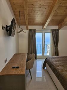 a bedroom with a bed and a desk with a view of the ocean at Otium Relais in Furore