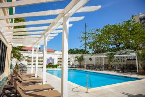 a pool with lounge chairs and a white pergola at Courtleigh Hotel & Suites in Kingston