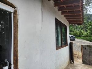 eine Seite eines Hauses mit Fenster und Auto in der Unterkunft Bangalô com Vista Parcial para o Mar in São Sebastião