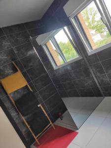 un baño en el ático con paredes y ventanas de baldosas negras. en chambres chez l habitant villa de luxe, en Mouvaux