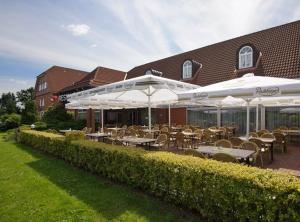 un restaurante con mesas y sombrillas frente a un edificio en Hotel Zur Windmühle, en Stapelfeld