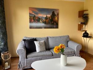 ein Wohnzimmer mit einem Sofa und einer Vase mit Blumen auf dem Tisch in der Unterkunft Ferienhaus Lisa am Silbersee in Frielendorf