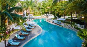 a swimming pool with lounge chairs and palm trees at Mahekal Beach Front Resort & Spa in Playa del Carmen