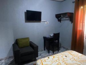 - une chambre avec un lit, une chaise et une télévision dans l'établissement Sunrise Center Bonapriso 104, à Douala
