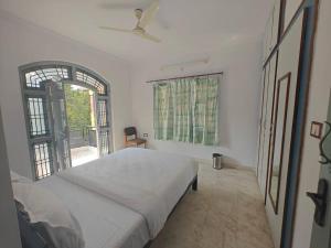 a white bedroom with a bed and a window at Waterfall Villa - 4BHK in Mysore