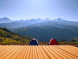 two people sitting on top of a roof looking at mountains at mountain view willcacocha lodge in Huaraz