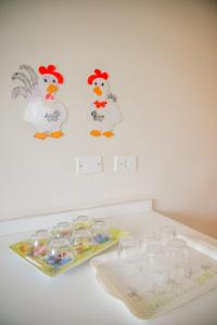 a white table with glasses on it with chickens on the wall at Paramar in Ubatuba