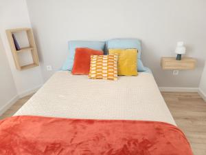 una cama con almohadas coloridas en una habitación en Paisible, spacieux avec petit jardin, en Artigues-près-Bordeaux