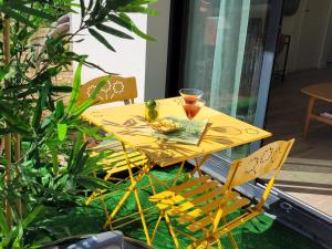 una mesa amarilla y sillas con una bebida encima en Paisible, spacieux avec petit jardin, en Artigues-près-Bordeaux