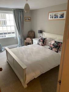 a bedroom with a large white bed and a window at Cosy beach house steps from the sea in Cromer