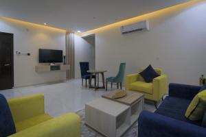 un soggiorno con sedie gialle e blu e TV di جراند فيوتشر a Abha