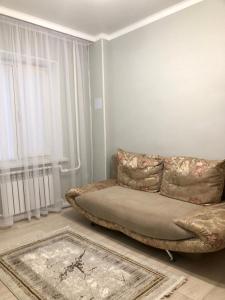 - un salon avec un canapé et une fenêtre dans l'établissement Apartment, à Taraz