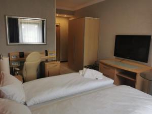 a hotel room with two beds and a flat screen tv at Hotel Alter Hof 