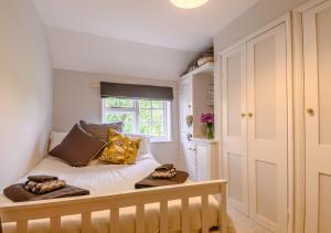 a bedroom with a bed with pillows and a window at Riverside Cottage in Snape