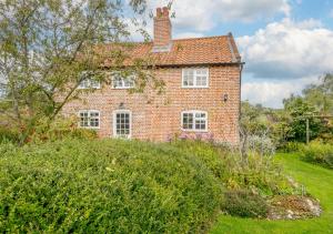 an old red brick house with a chimney at Riverside Cottage in Snape