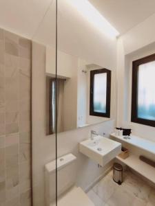 Baño blanco con lavabo y espejo en Antigua Casa Hermandad en Sevilla