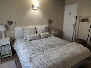 1 dormitorio con cama con edredón y almohadas blancos en Gîte Les Piraudières, en Noyant-de-Touraine